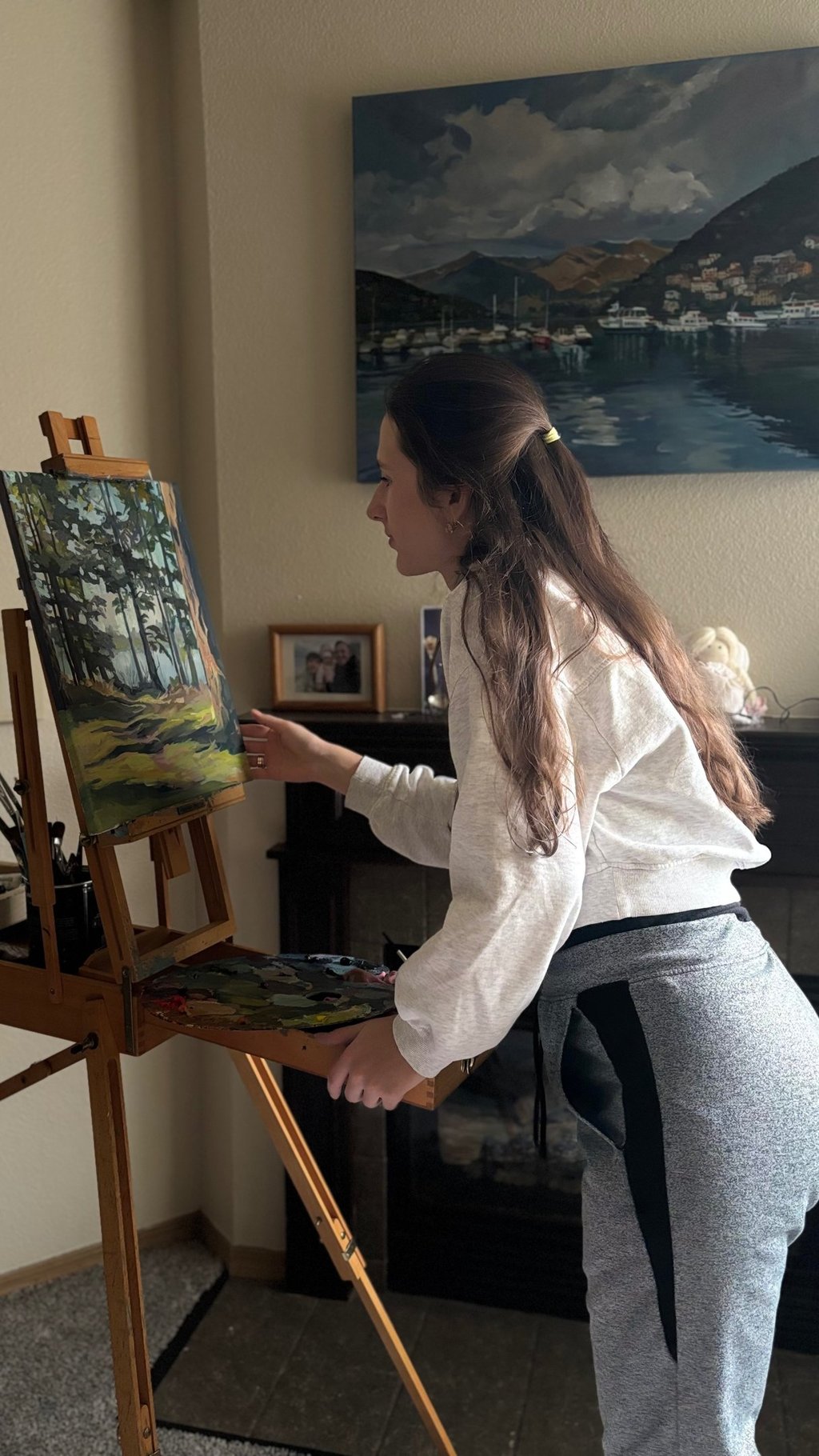 Angela Moiseieva painting at her easel in a bright art studio.
