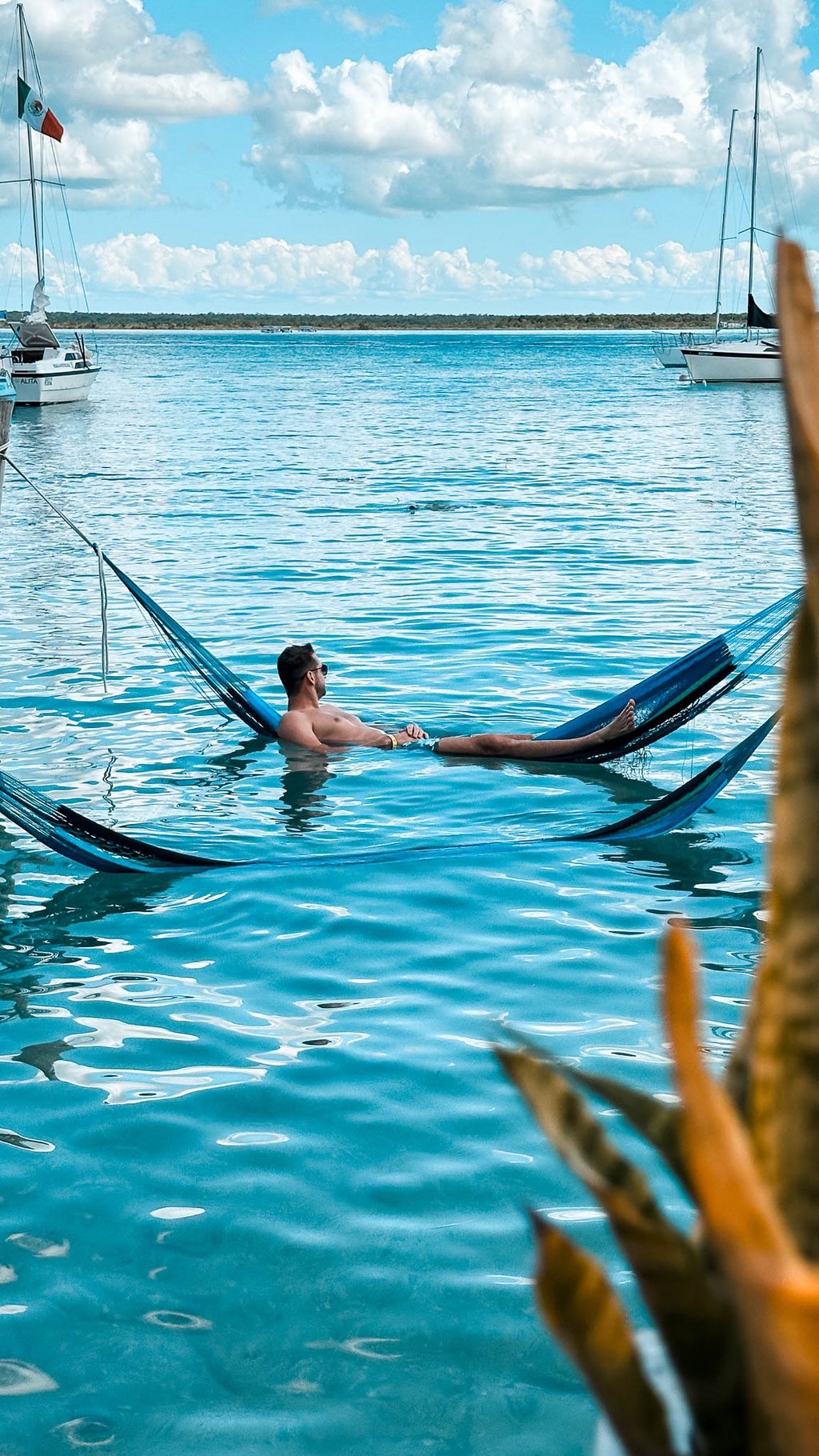 Mann in Hängematte im Wasser Bacalar Mexiko Beachclub