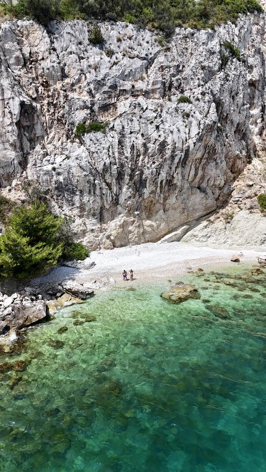 Aerial panoramic view of a hidden beach, a couple and dramatic cliffs on Ciovo during a private boat tour from Split, Croatia