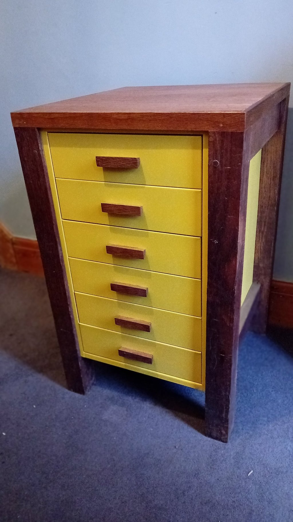 Bright yellow metal filing drawers with wooden handles with a wooden frame, legs and top