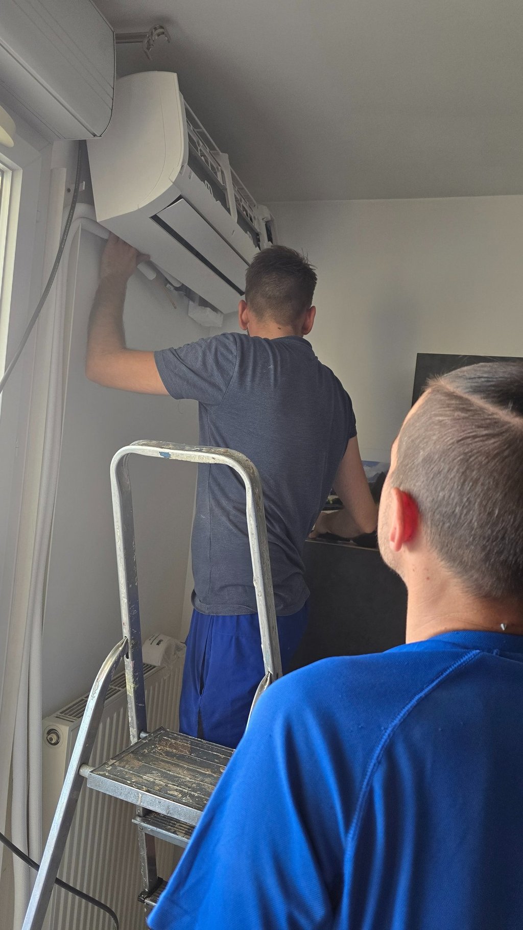 Repairing a refrigeration leak on a wall-mounted unit.