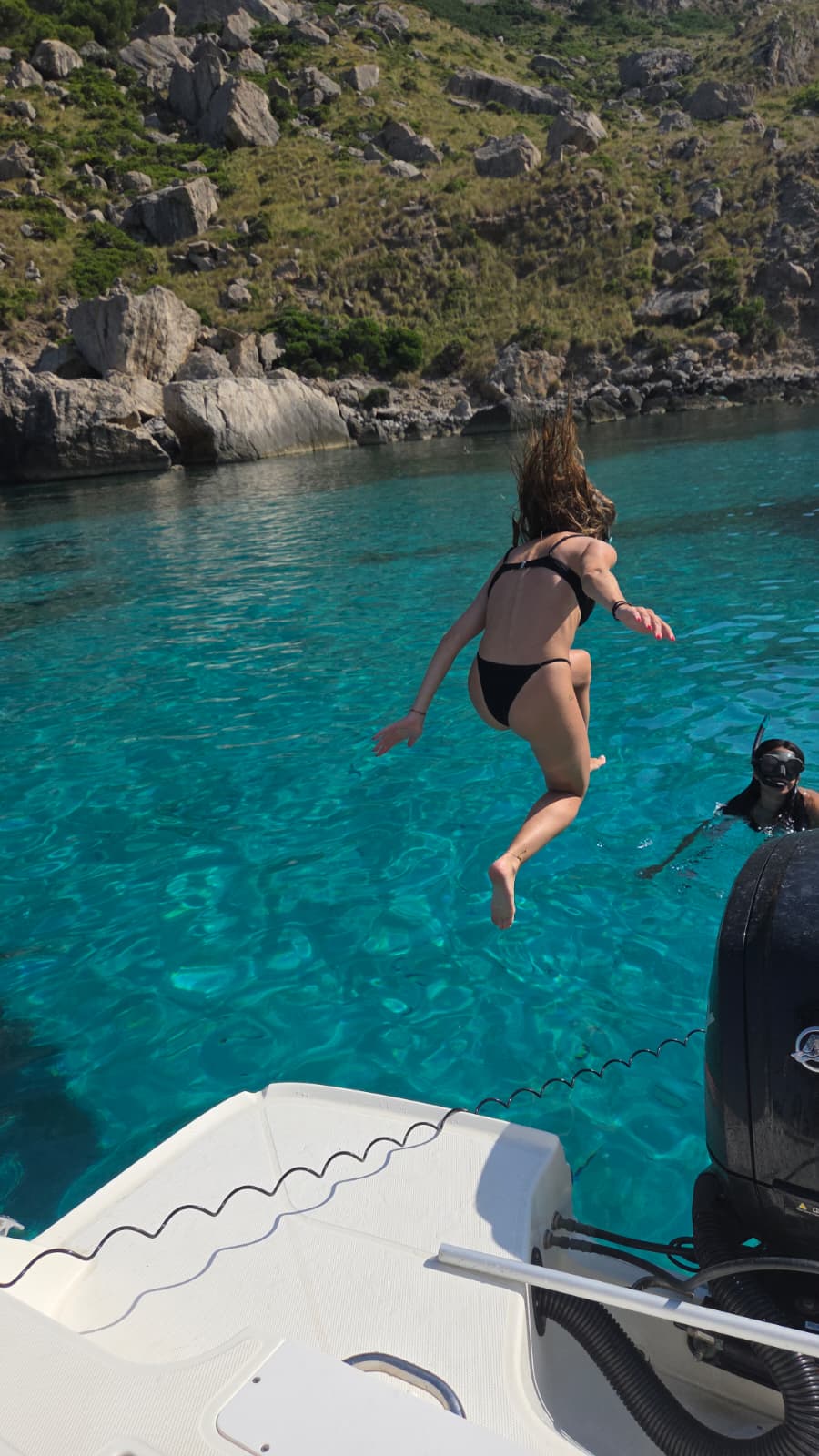 une jeune femme sautant dans la mer depuis un bateau