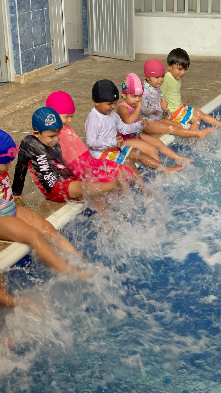 Niños pataleando el agua de una piscina en clase de natación en Aqua Fit Actividad de Ukelele Jardín Infantil