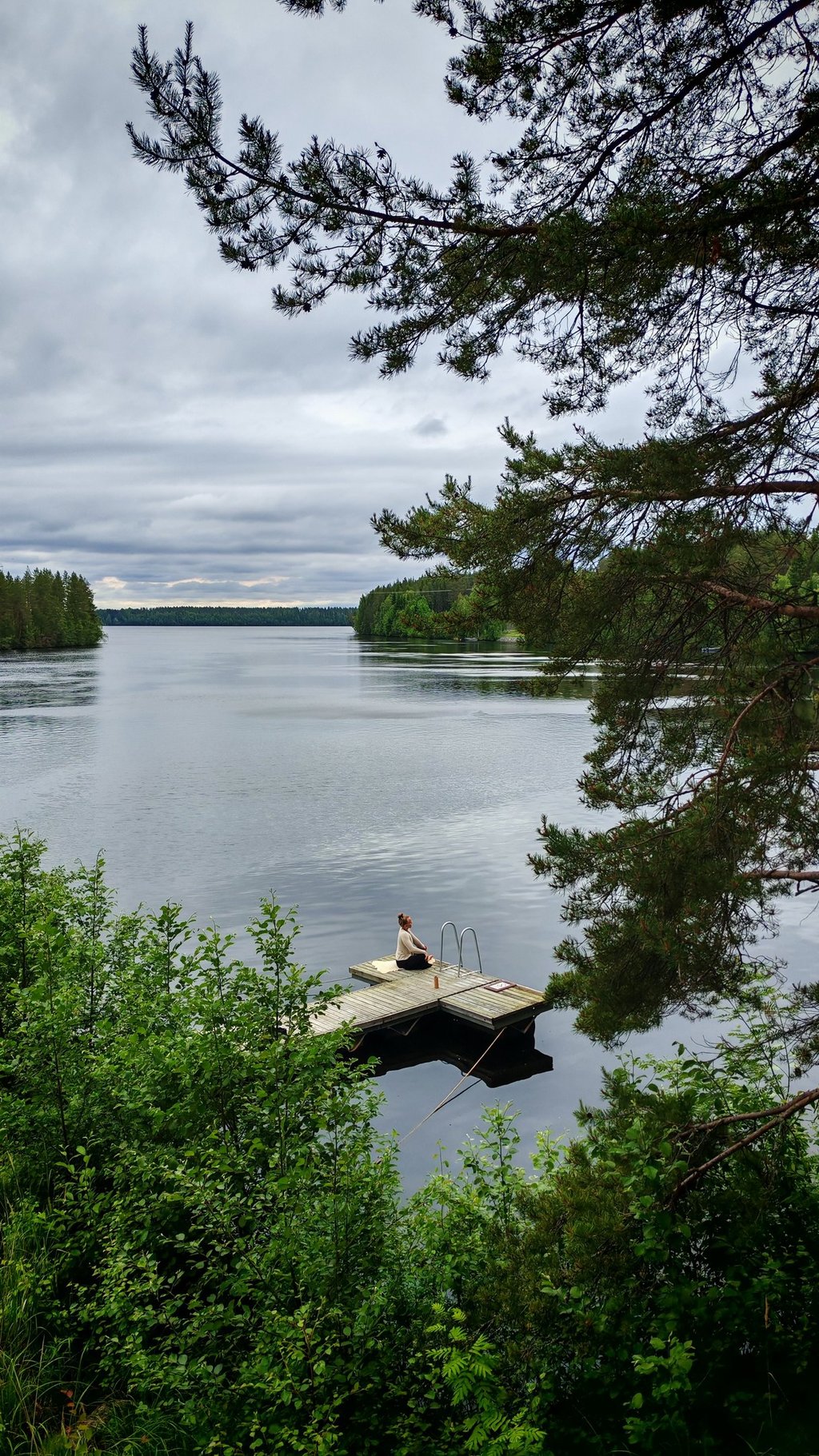 Person relaxing on a lakeside dock at a quiet forest lake in Rokua Geopark near Nature Dream Days, s