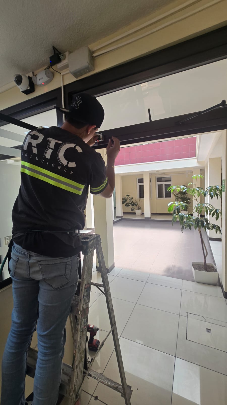 Técnico instalando sensor o botón de acceso en marco de puerta.