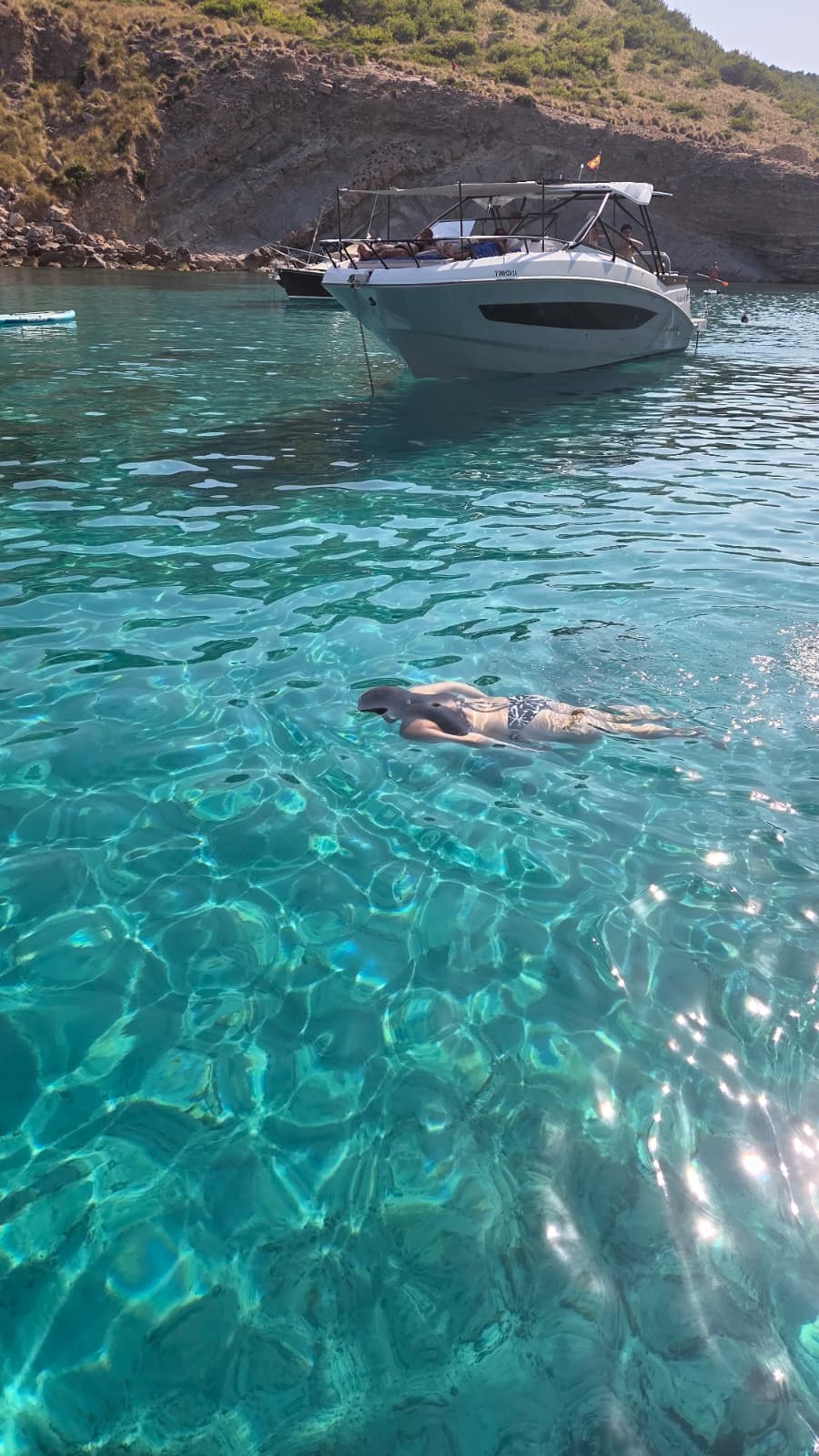 Jeune femme nageant dans une eau turquoise.