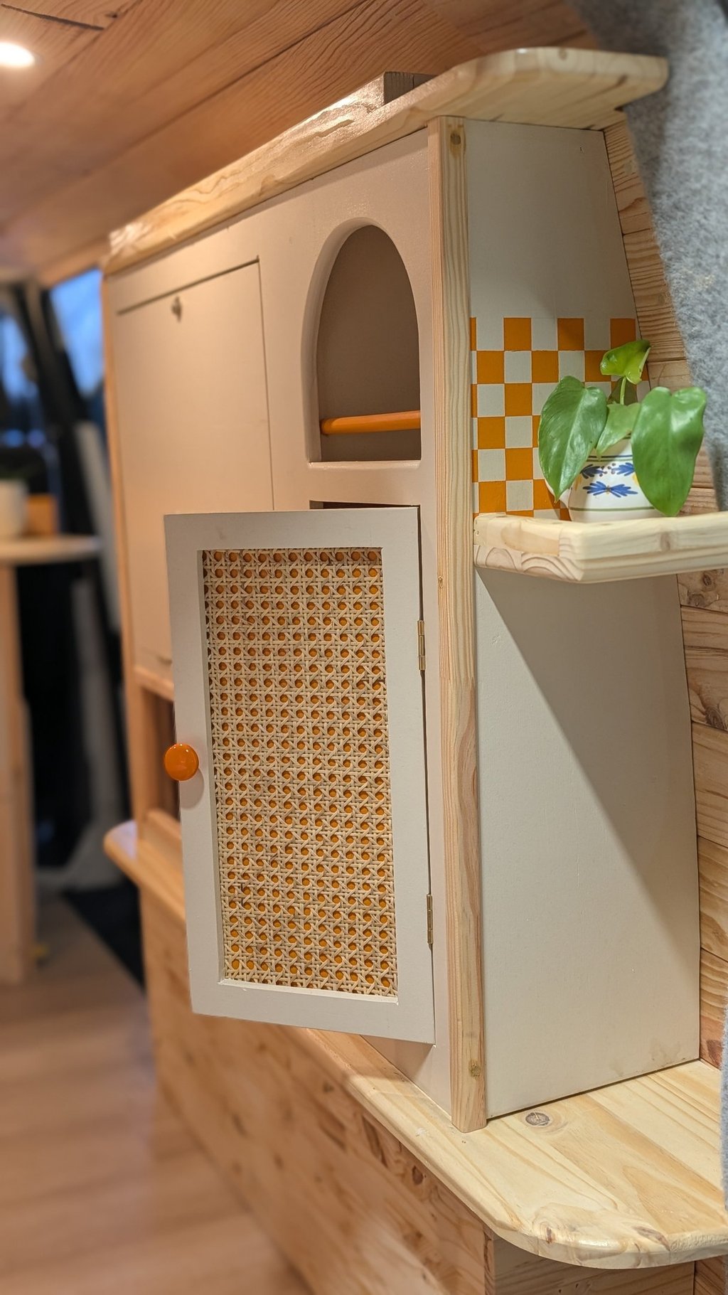 Détail mobilier de van en bois avec porte en cannage et crédence damier orange, style bohème et chal