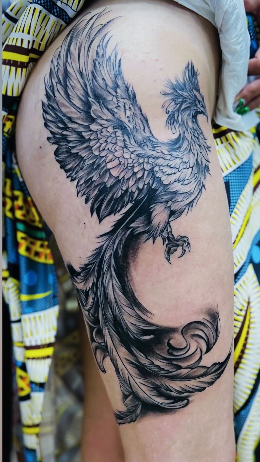 Black and grey phoenix tattoo on upper thigh, professional tattoo studio in Hurghada”