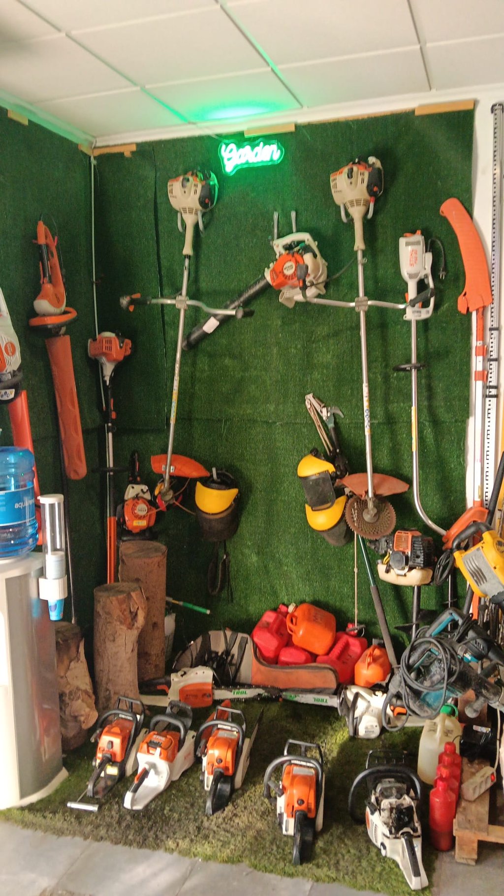 Professional Stihl chainsaws and garden power tools organized on a green grass wall display.