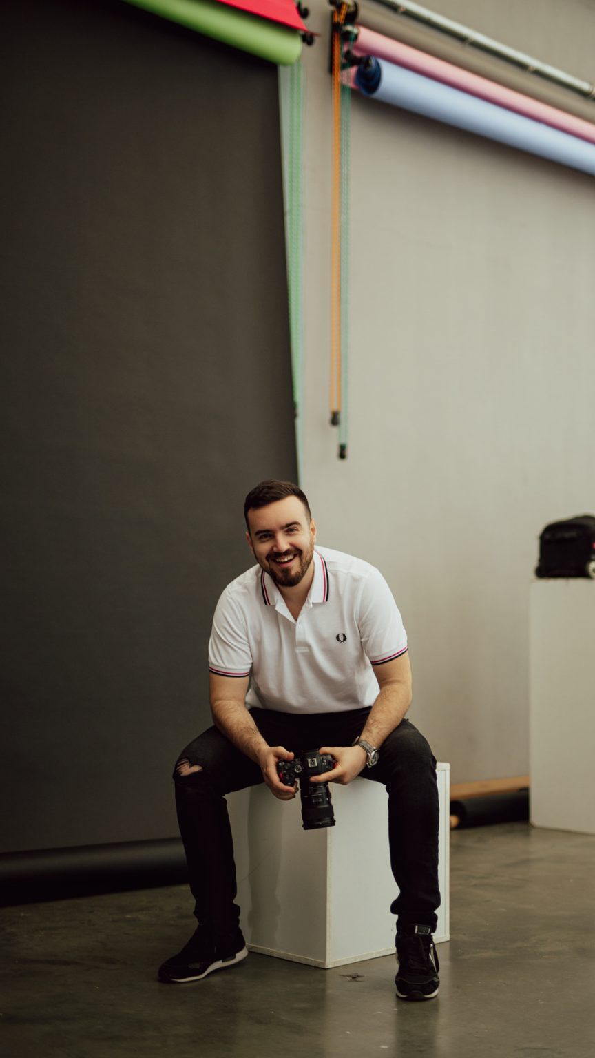 a man sitting on a white cube with a camera