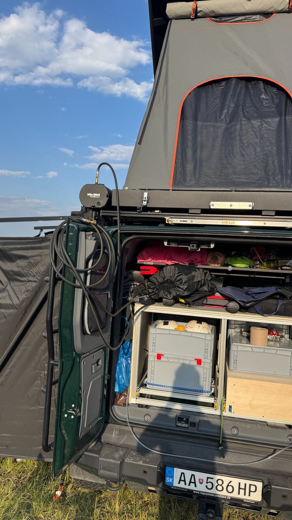 Off-road camper van setup with a rooftop tent and organized storage drawers.