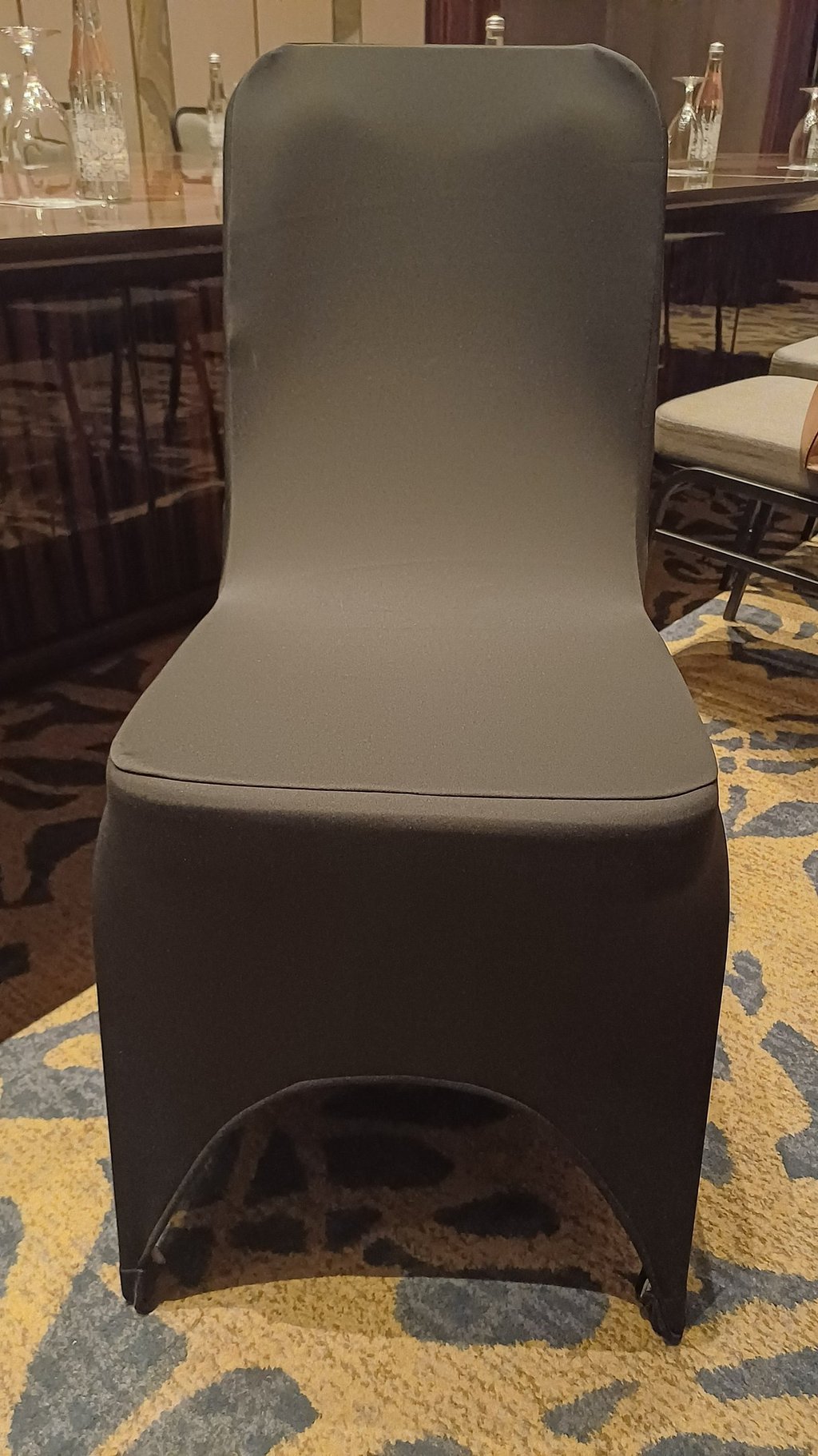 A sleek charcoal gray spandex chair cover for banquet and wedding event seating.
