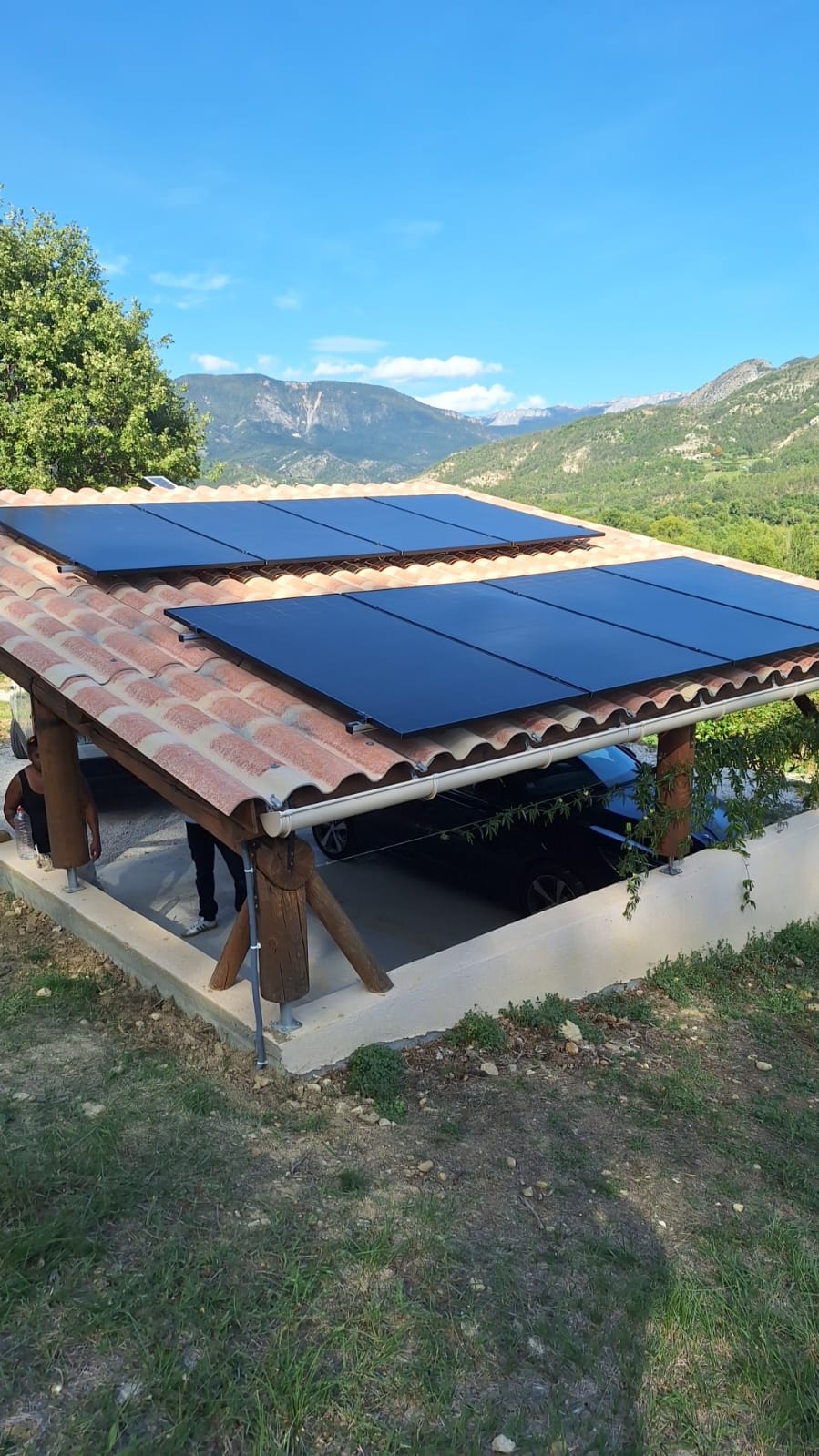 Panneaux photovoltaïques installés sur carport en plaques PST à Mézel, vue rapprochée avec paysage en arrière-plan.