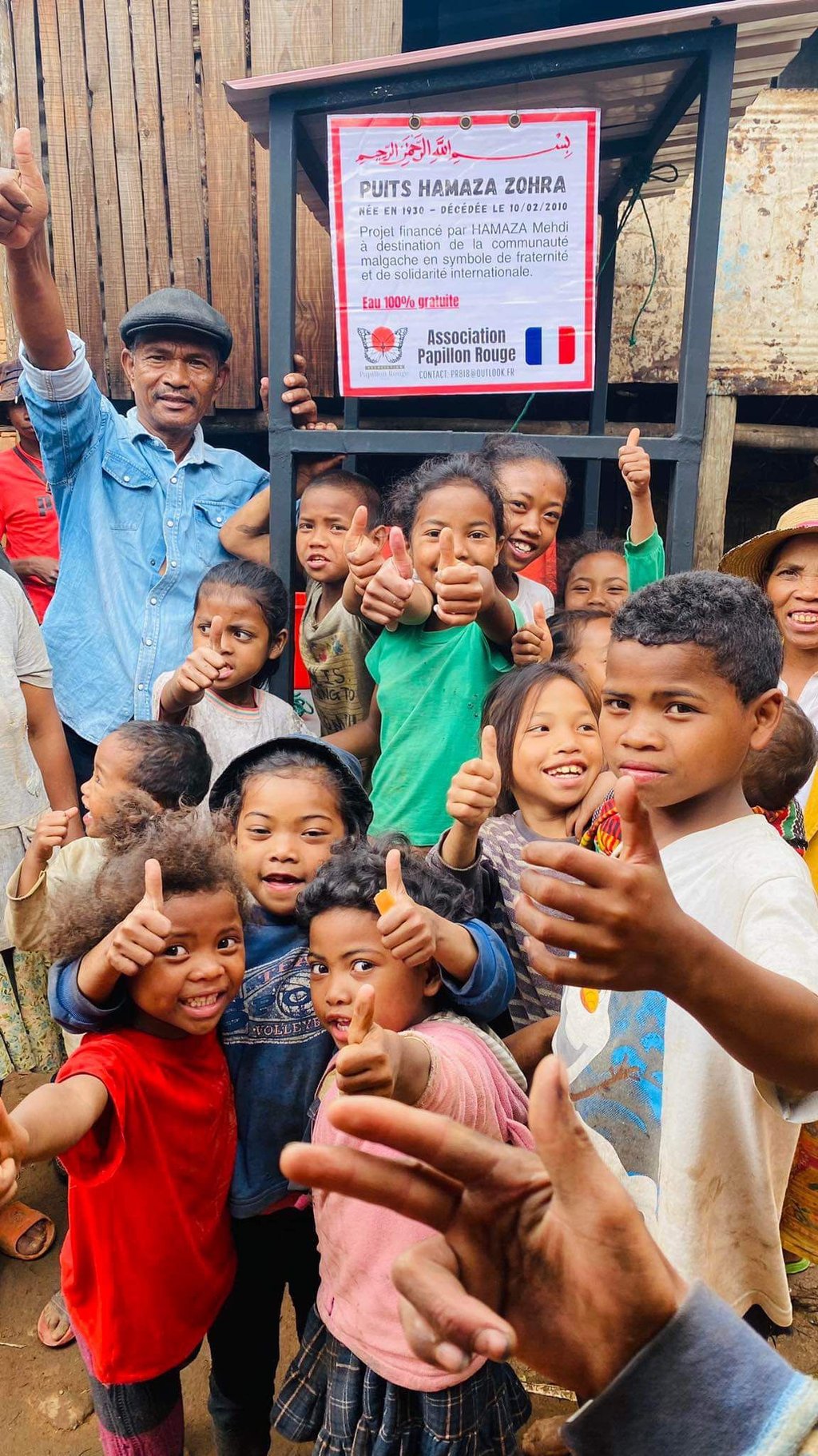 a group of children and adults standing in front of a sign