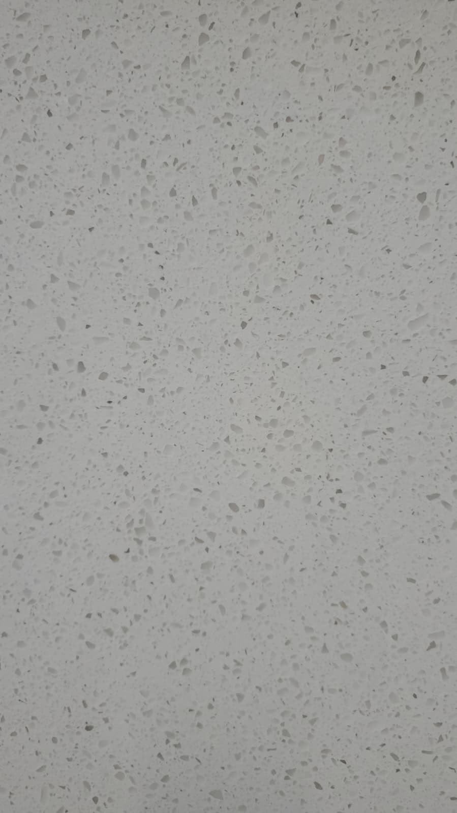 Close-up of light gray quartz slab with speckled texture