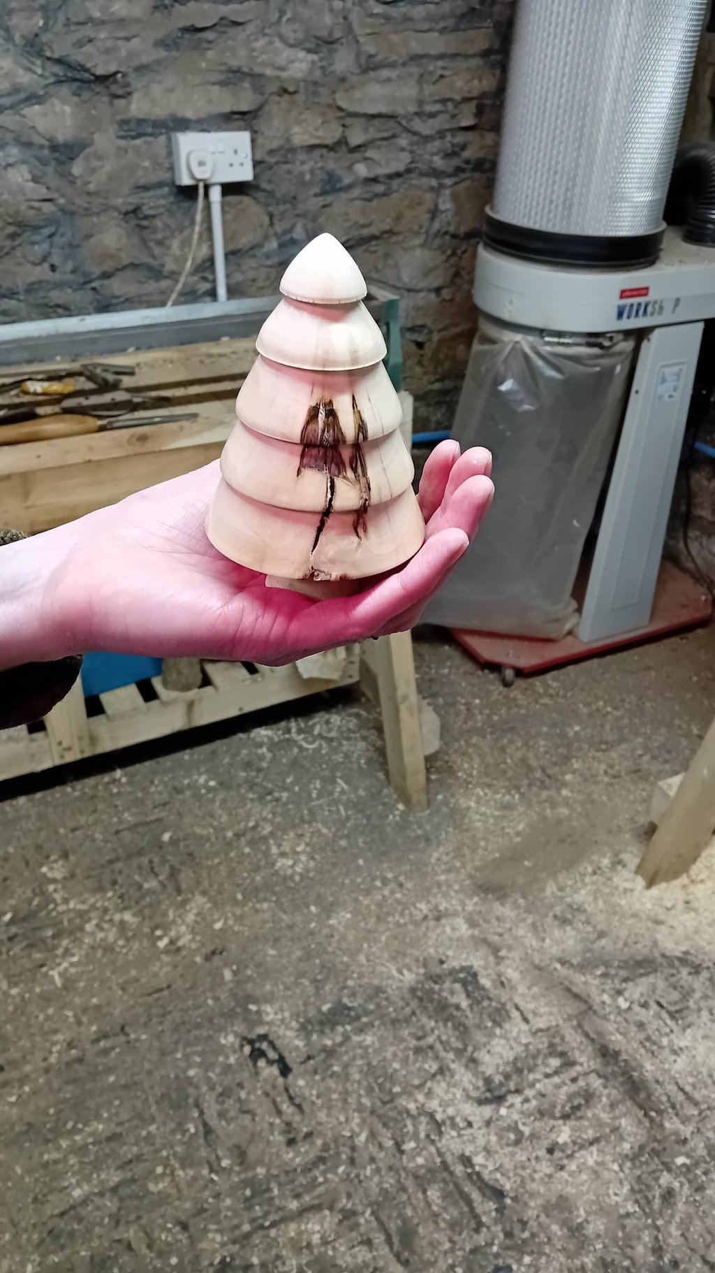 A turned wooden fir tree standing on a hand