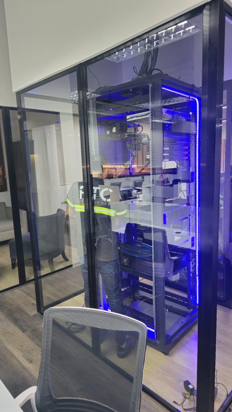 Técnico trabajando dentro de cuarto de servidores con gabinete iluminado.