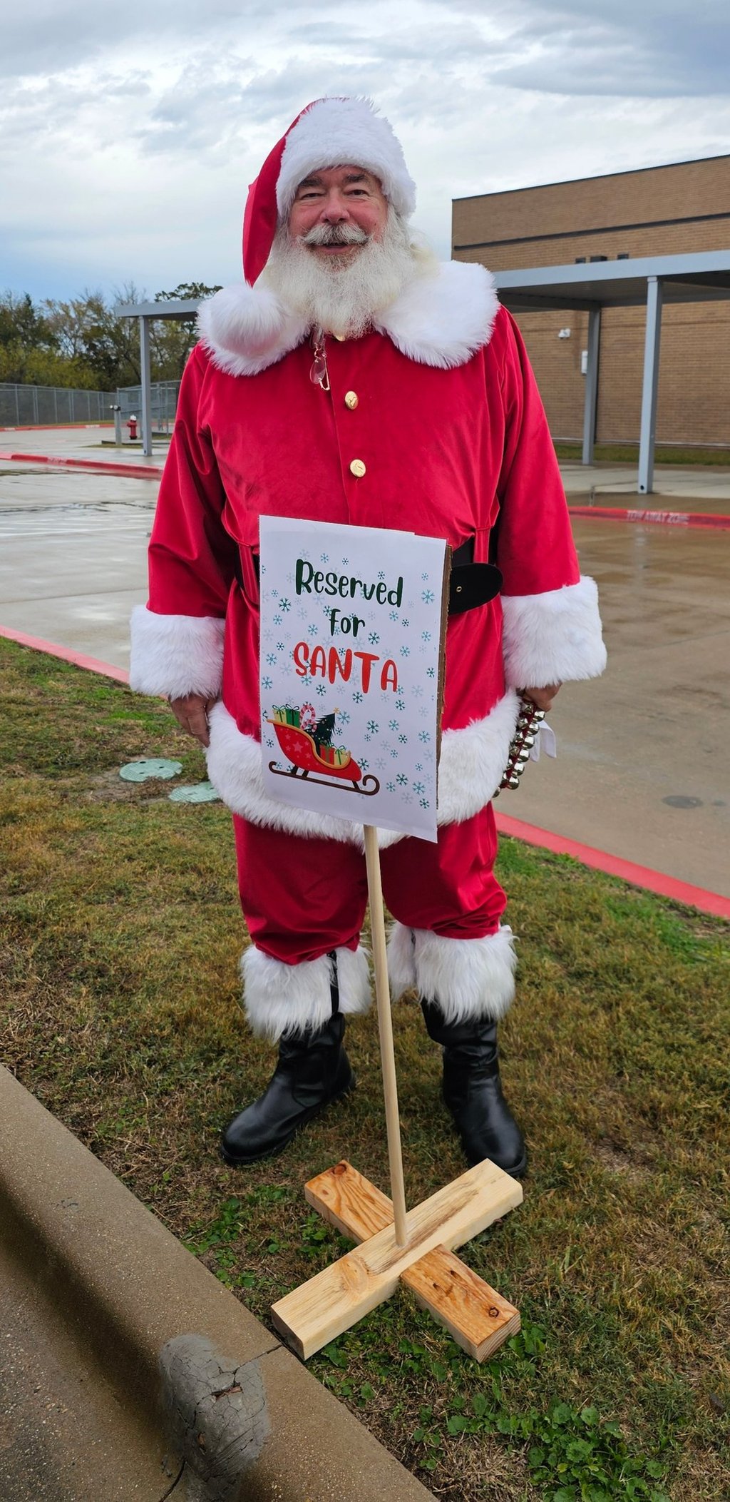 The Santa Cowboy standing behind his "reserved " parking sing at Spring Creek Elemtary school visit