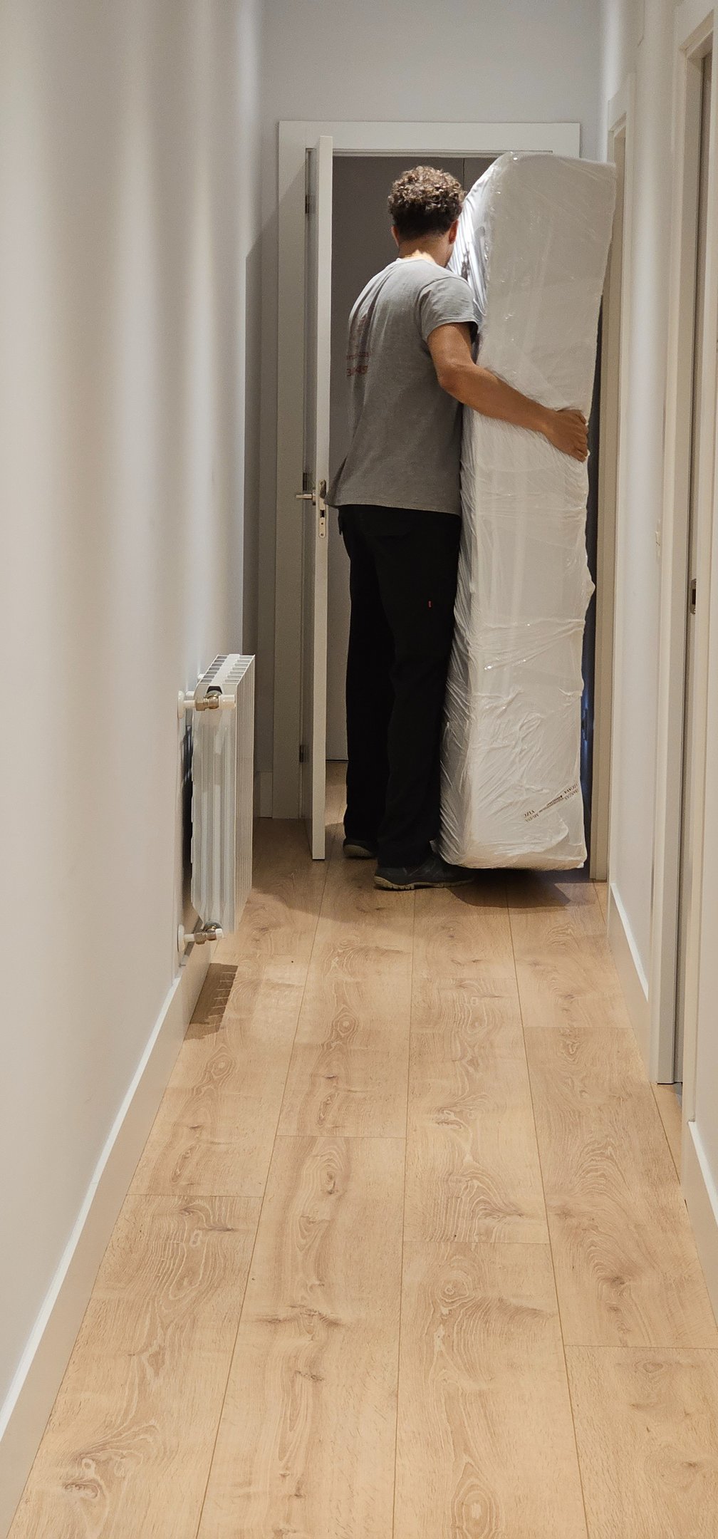 a man is moving a mattress in a hallway