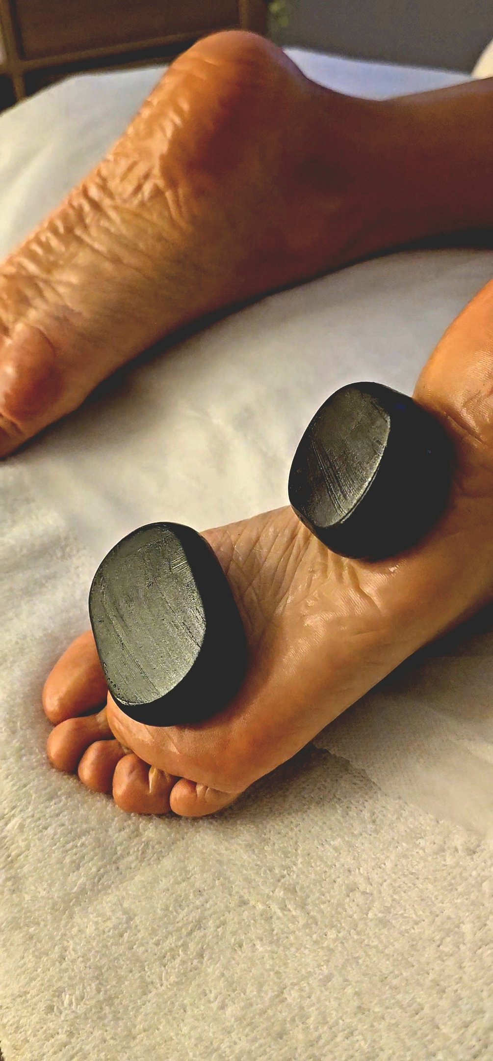 detalhe de uma massagem com pedras quentes sendo feita nos pés