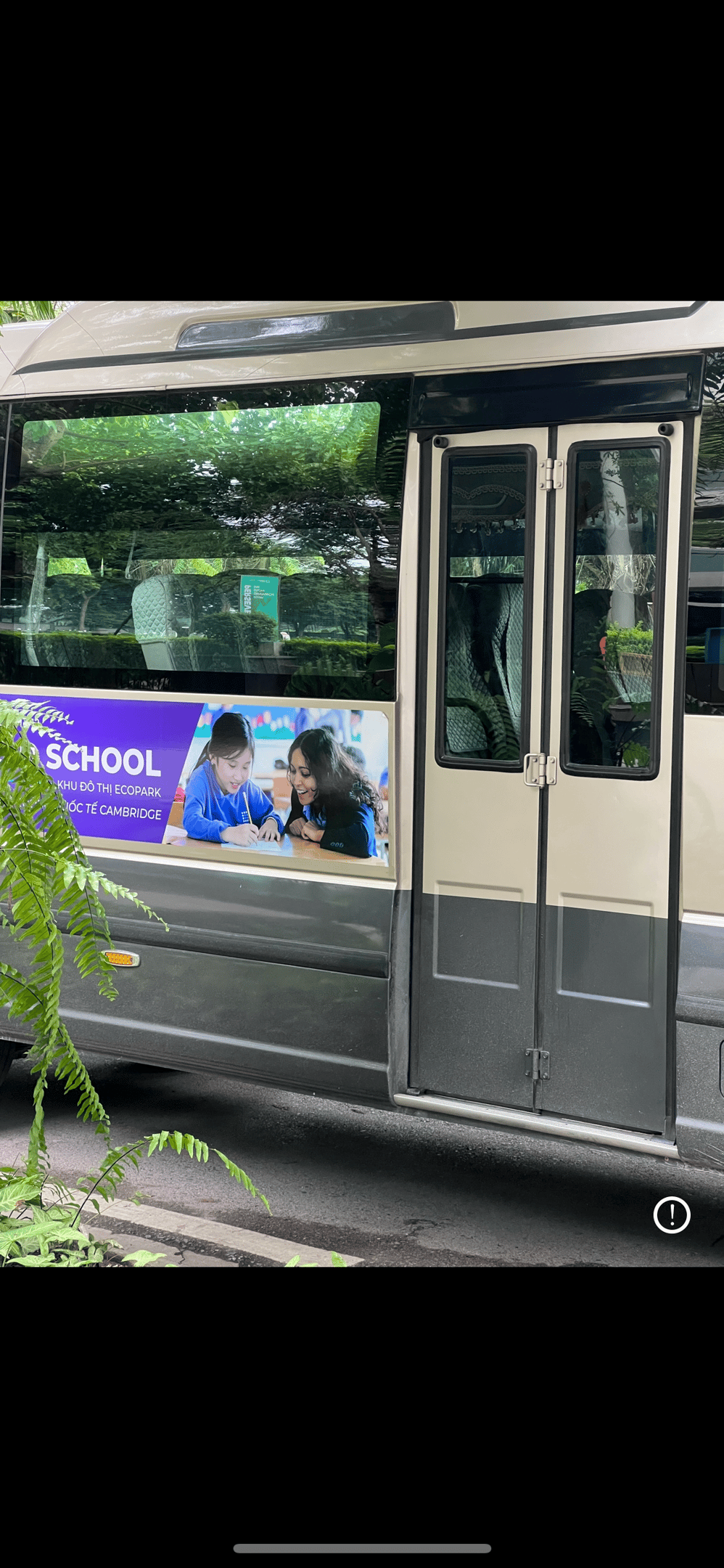 A bus with a advertisement of a school. The advertisement has a female teacher teaching students.