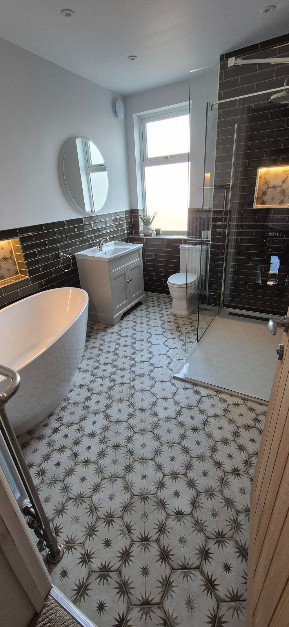 Modern bathroom featuring patterned floor tiles, a freestanding bathtub, and walk-in glass shower.