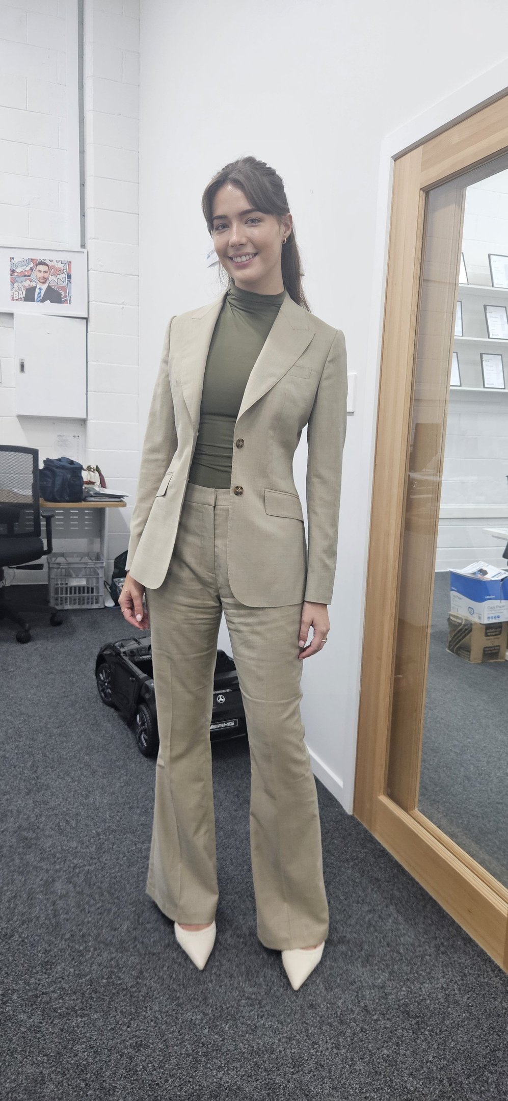 a woman in a suit and heels standing in a room