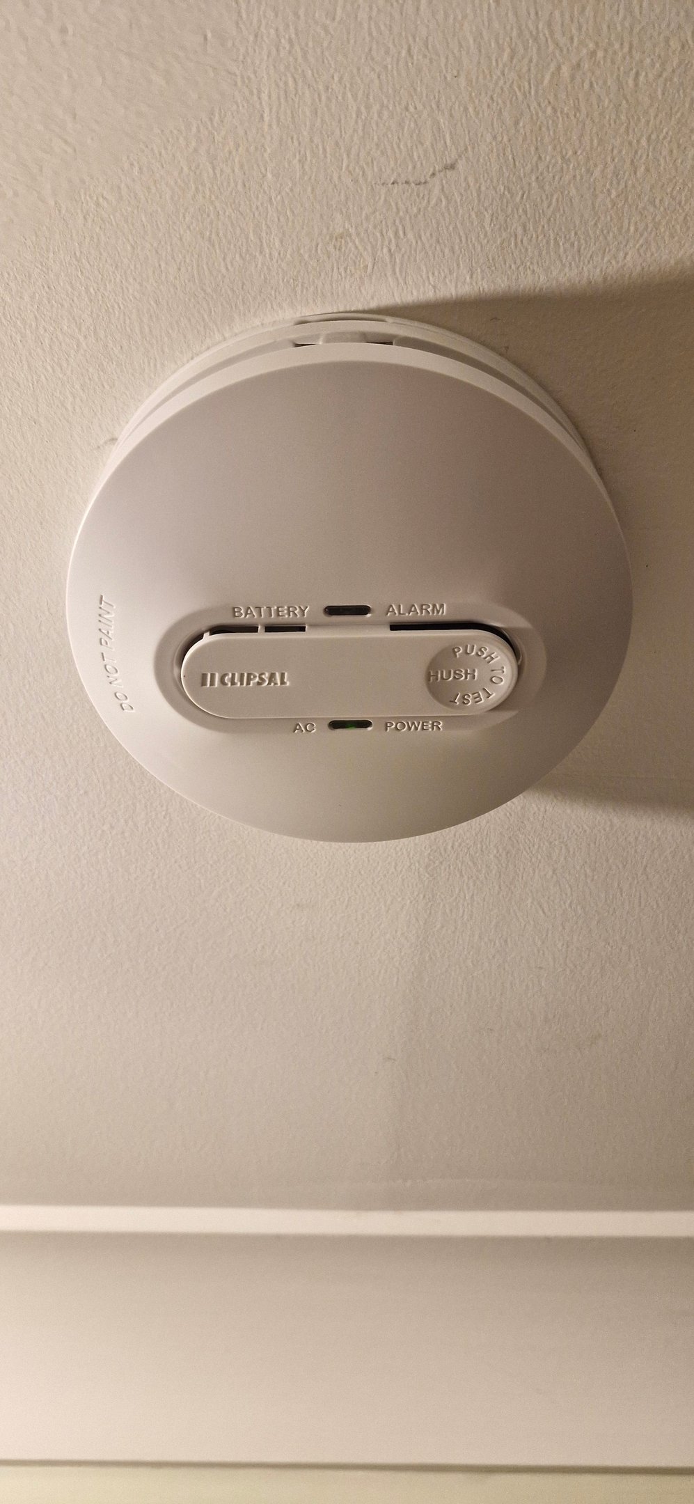 White Clipsal smoke alarm mounted on a ceiling with power and battery indicators.