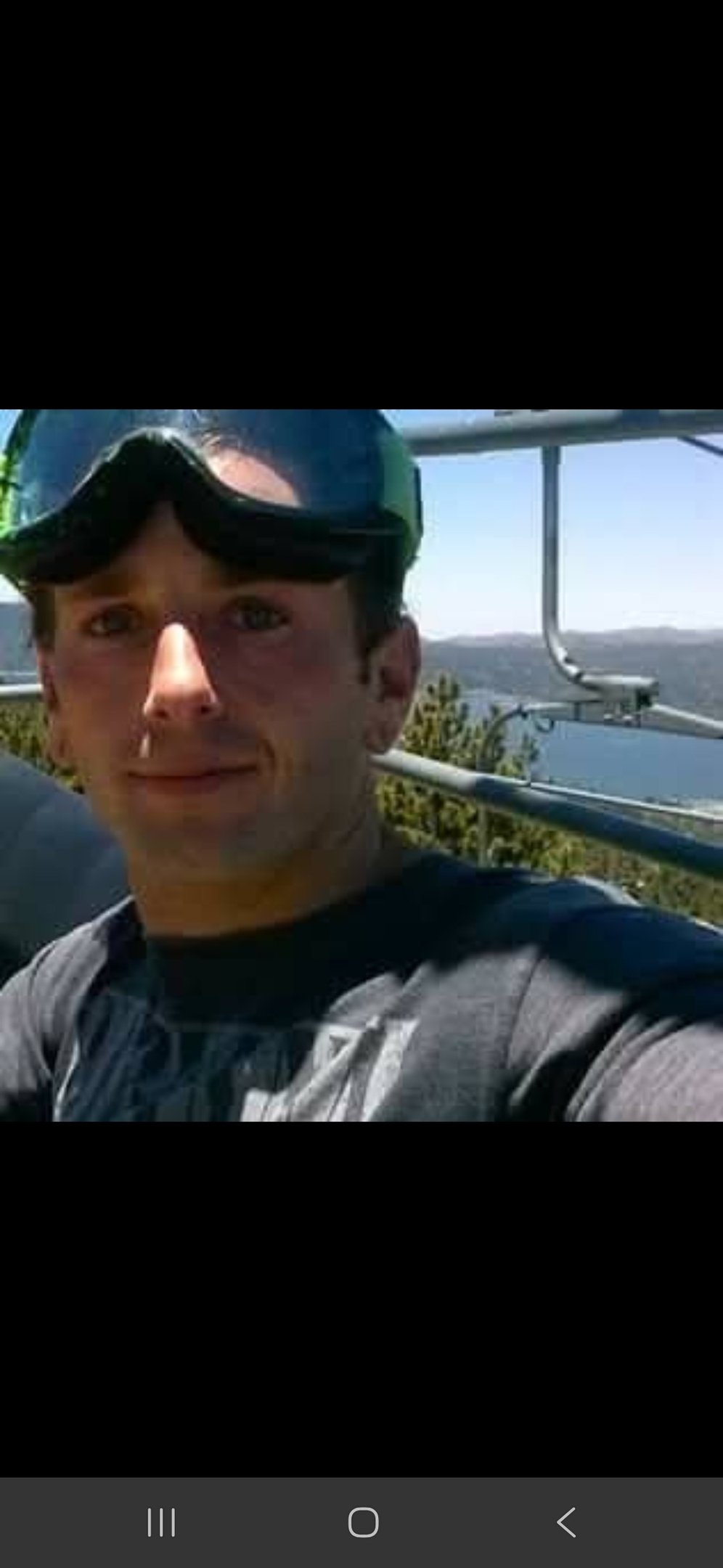 riding up a chairlift with goggles on head