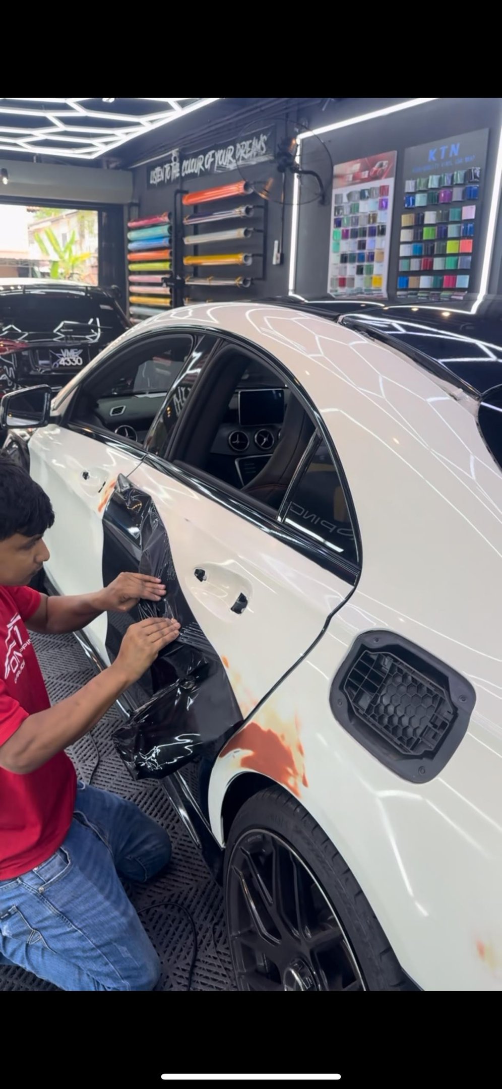 Technician removing old vinyl wrap film from car door panel