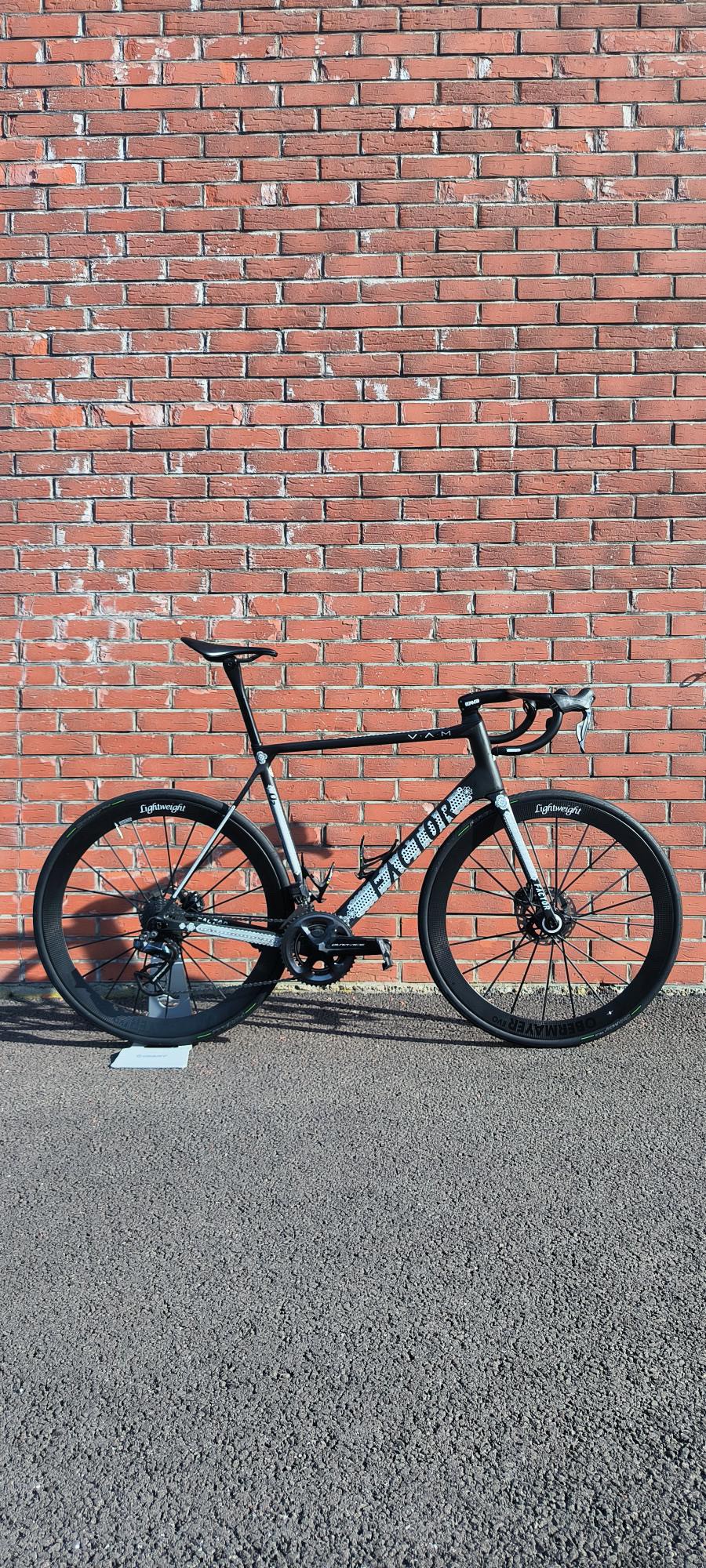 a custom Factor O2 parked on the side of a brick wall