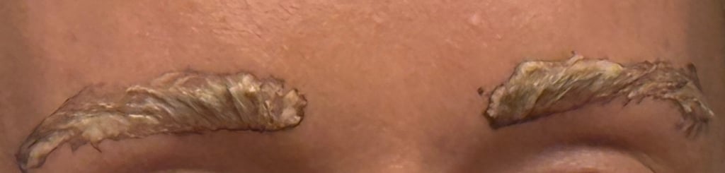 Eyebrows with tint applied and processing during at home eyebrow tinting routine.