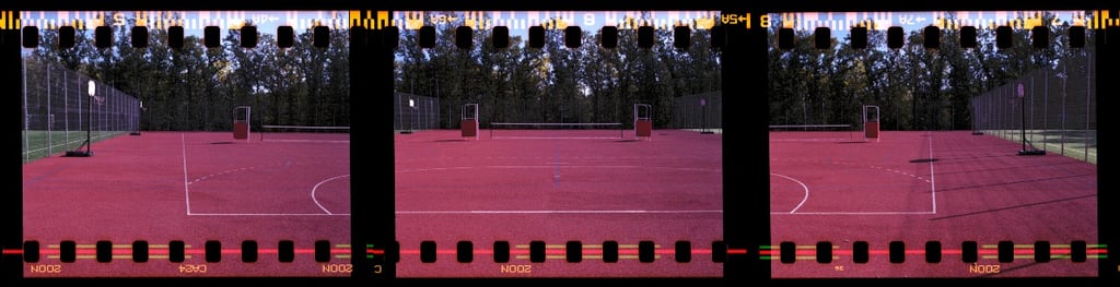 Composed photo of a vibrant red outdoor multipurpose sports court with crisp white markings