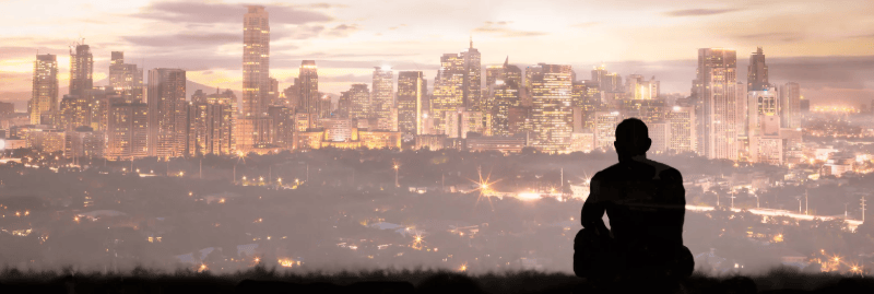 Image of mysterious man looking at the sun setting behind sky scrapers