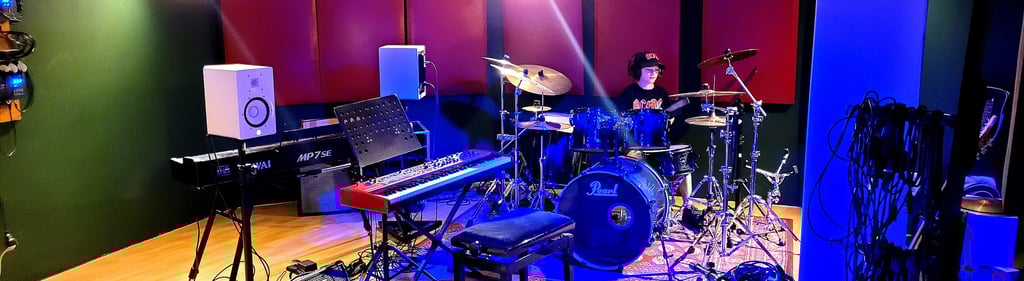 a recording studio with a e-piano, drums, and Keys