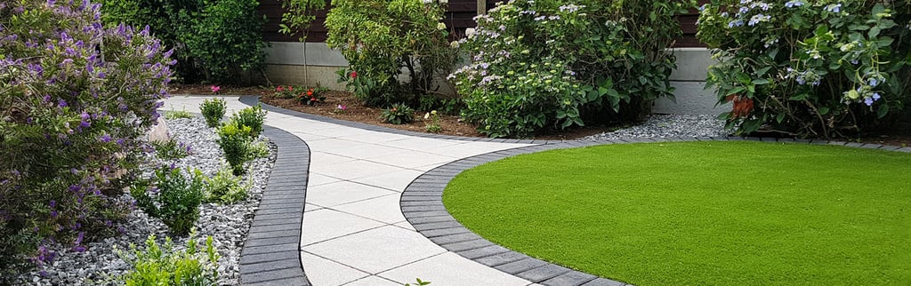 Patio with custom stone circle with aggregates and paving weaving through adventurous garden design