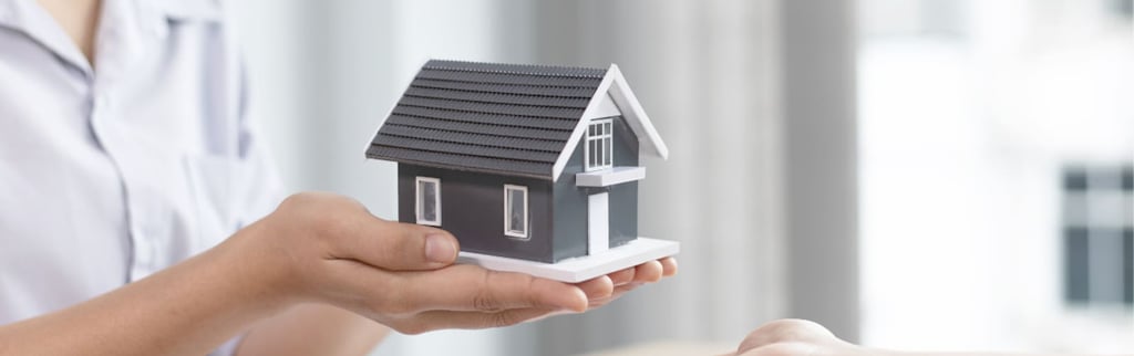 a woman holding a small house model
