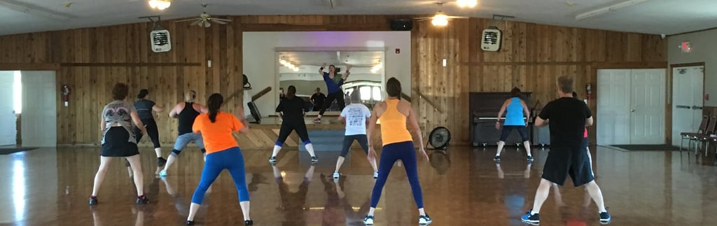 Melody teaches a Zumba class in a large dance hall.