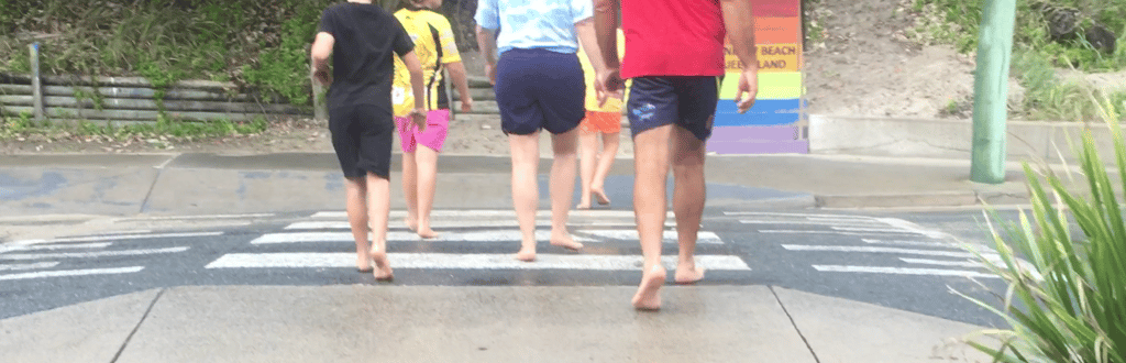 A barefoot Australian family crossing a pedestrian crossing