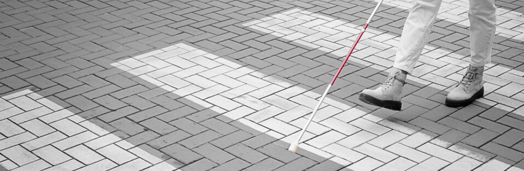 Blind person walking through city with white cane