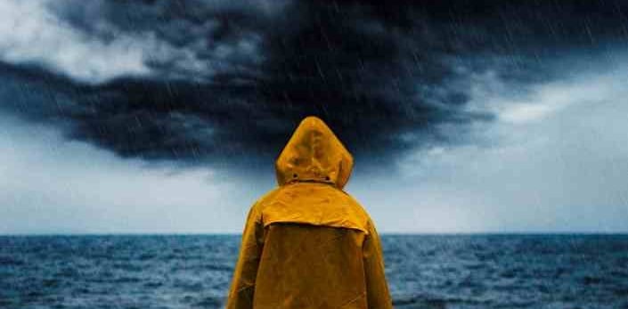 person in oilskins looking out to a stormy sea