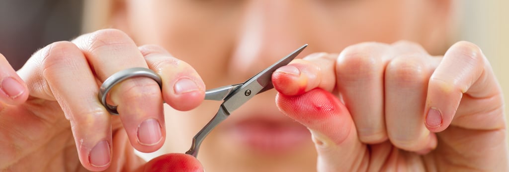 ragazza che cerca con la forbicina di tagliarsi le cuticole 