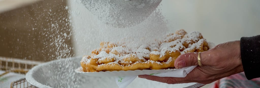 a funnel cake being dusted with powdered sugar