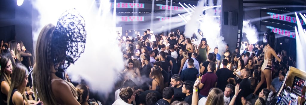 a crowd of people standing around a dj booth, rico sanchez performance at La V in Miami