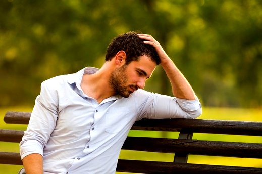 a man sitting on a bench in a park need to write his cv