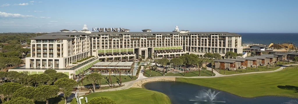 Aerial view of Cullinan Belek luxury resort featuring a golf course, lake, and Mediterranean beachfront.