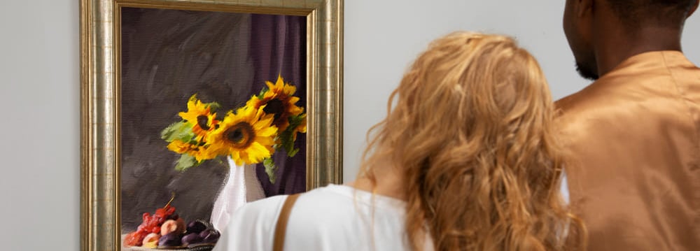 a man and woman looking at a painting of a sunflower
