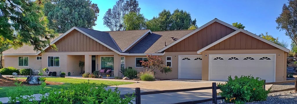 Ranch style home remodeled with tan lap siding, white trim, and brown board and batten gable.