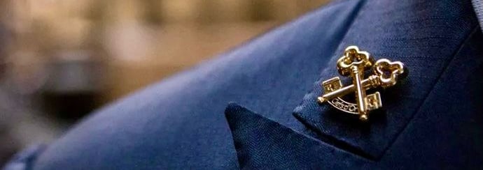 a man in a suit and tie with a gold anchor on it