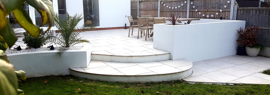 Modern chic raised porcelain patio with white rendered walls and planters